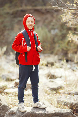 Happy smiling hiker boy with backpack in forest. Dressed in red sweatshirt.の写真素材