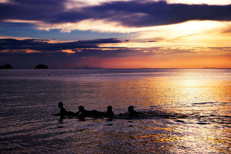 Playing and swimming kids in sea over beautifil sunrise in Thaiの写真素材