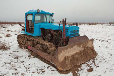 Old and rusty blue tractor on fieldの写真素材