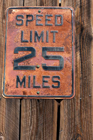 An old, rusty speed limit sign on weathered woodの写真素材