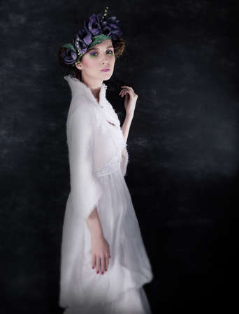 Attractive  young woman in white clothes and blue wreath of flowers posingの写真素材