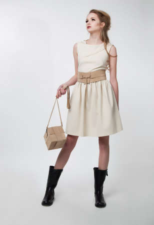 Lovely young female in modern dress with handbag posing in studio. Series of fashion photosの写真素材