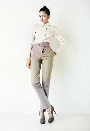 Young stylish brunette woman in white shirt and trousers isolated on whiteの写真素材