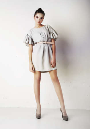 Attractive stylish young brunette female fashion model posing over white wallの写真素材