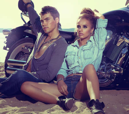 Two people and bike  fashion woman and man sitting by motorbike and resting  Adventure and vacations conceptの写真素材