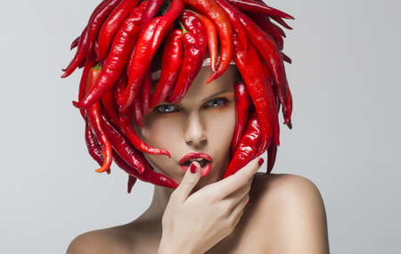 Portrait of fashion trendy woman with red chili pepper as a headwearの写真素材