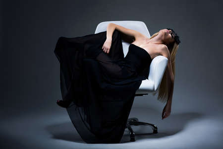 Harmony & Sensuality. Romantic Blond Female in Black Dress resting in Armchair. Satisfactionの写真素材
