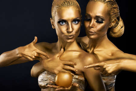 Masquerade. Enjoyment. Two Glossy Women with Golden Body Art. Glamorの写真素材