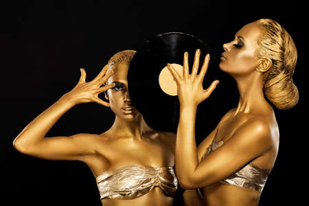 Fetish. Women DJs holding Retro Vinyl Record. Fantastic Gold Badyart. Performanceの写真素材