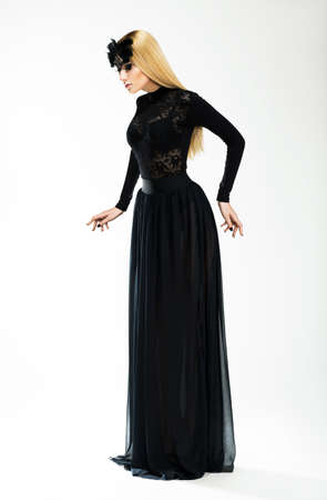 Nostalgia. Expression. Beautiful Blond In Long Retro Dress and Black Maskの写真素材