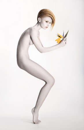 Imaginary. Expressive Undressed Woman in Fantastic Graceful Pose. Statue with Flowerの写真素材