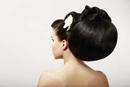Haircare. Backside of Fashion Model with Creative Hairstyle. Smooth Healthy Black Hair with Flower. Spa Salonの写真素材
