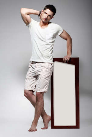 Elegant Young Man in White Cotton Clothes with Board Standingの写真素材