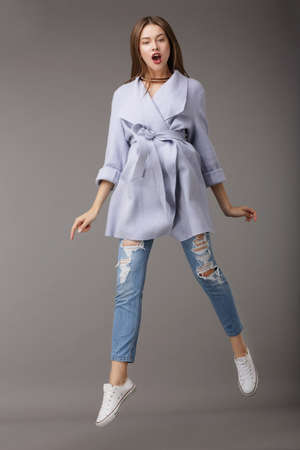 Trendy Young Female Jumping in Blue Coatの写真素材