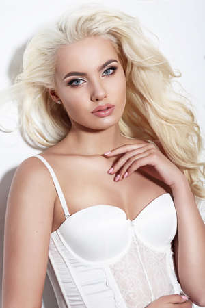 Portrait of beautiful blonde woman .  Long Blond Hair. Posing in the studio on a white background. Gorgeous blonde model in fashionable corselet . Sexy woman in swimsuit.の写真素材