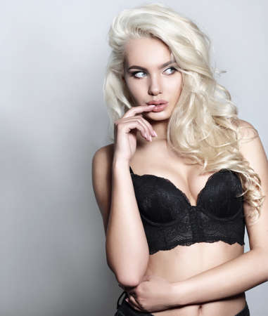 Photo of sexy blonde young girl in a black bustier, posing in studio.の写真素材