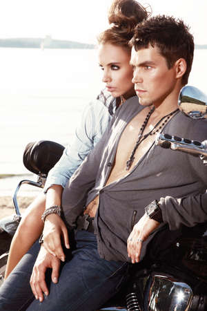 Romantic young couple in casual clothes sitting on a motorcycle.の写真素材