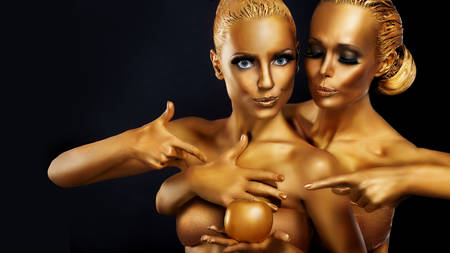 Portrait of a girl with golden body art posing with golden apple in her hands.の写真素材