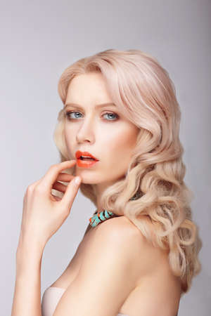 A blonde woman with a gentle makeup. Portrait. Finger touches lips.の写真素材