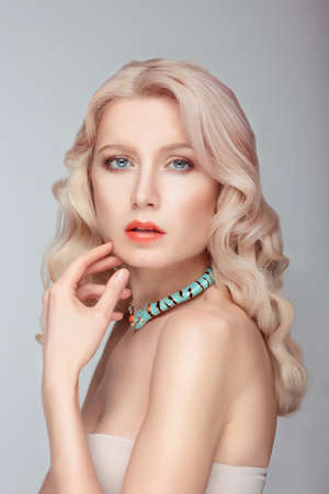 Portrait of a young blonde woman with a gentle makeup. Hand near the face.の写真素材