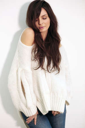 Young woman looking down and smiling. Against the backdrop of white walls, natural makeup.の写真素材