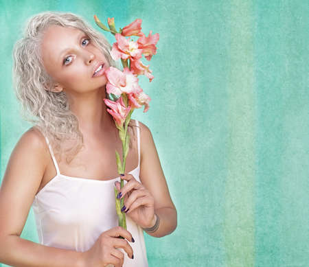 Portrait of a beautiful blonde woman on a green background with lily flower in hand.の写真素材