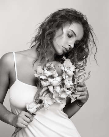 Young beautiful woman holding a flower, black and white. Sepia.の写真素材