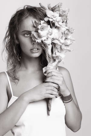 Young beautiful woman holding a bouquet of flowers. Close face. Black and white.の写真素材