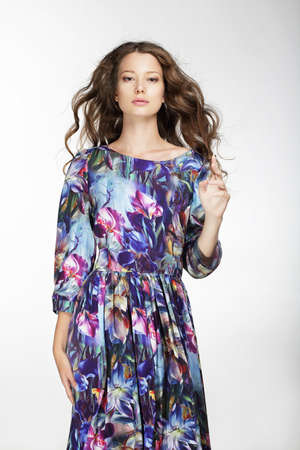 Young cute woman posing in studio, hand sign. Long blue dress, hair flying. Clean skin.の写真素材