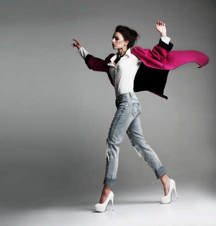 Beautiful stylish woman in a fashionable coat, walks in the studio. clothes flying. Fashion.の写真素材