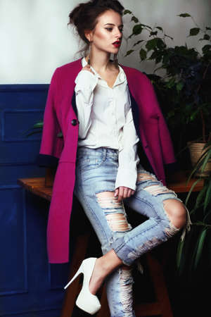 Stylish female model posing in bright clothes in a room with green plants.の写真素材