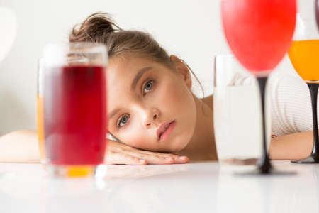 Closeup portrait. The girl's face between the glasses with drinks.の写真素材