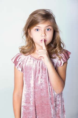 Cute girl shows sign of silence. Secret. Finger near the lips.の写真素材