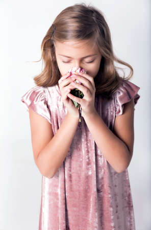 Girl holding a rose near the nose. Smell the flower, inhale the aroma.の写真素材