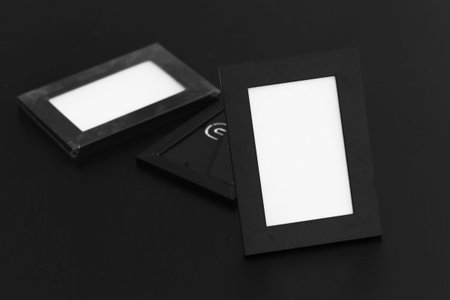Empty black photo frames on the black wooden table background. Small noice, focus put on the first frame. Vintage style.の写真素材