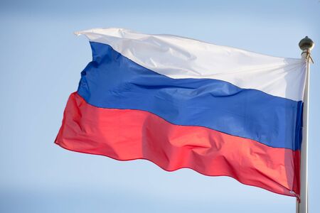 Official russian flag on the blue sky background.の写真素材