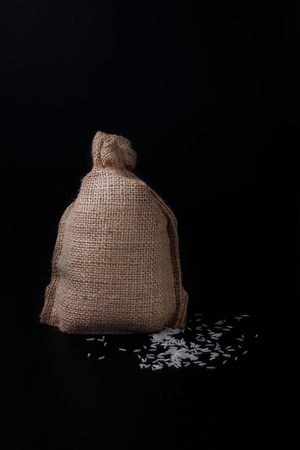 Bag of rice on black background. Old style. With several white rie grains outside.の写真素材