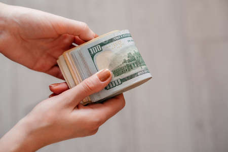 A woman hand holds a stack of 100 dollar billsの写真素材