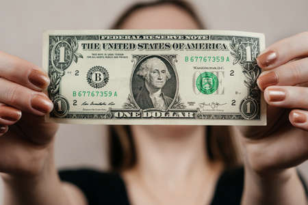 A girl holds a one dollar in front of her.の写真素材