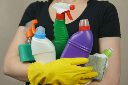 Cleaning. A woman wearing yellow gloves holds cleaning supplies and spongesの写真素材
