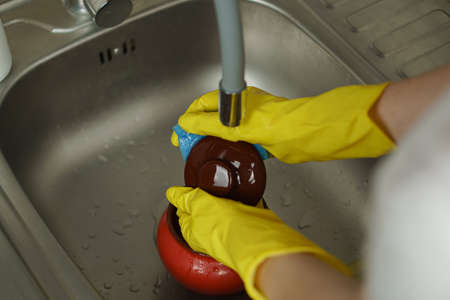 Woman in yellow rubber gloves washing dishesの写真素材