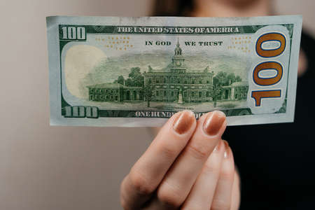 A woman holds 100 dollar bills in front of herの写真素材