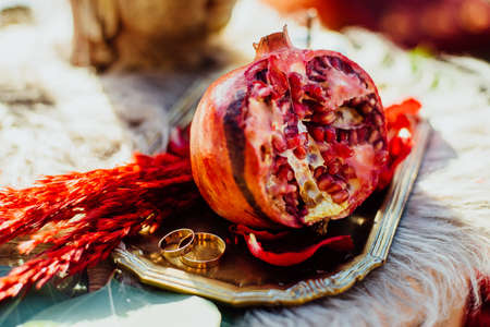 Wedding rings and pomegranate are on the trayの写真素材