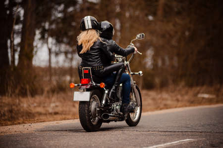 A couple of bikers a girl and a guy ride on the same motorcycle on the roadの写真素材
