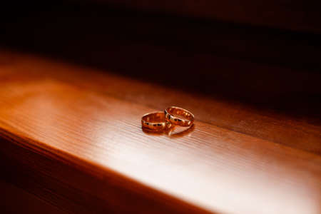 Wedding rings lie on a wooden table.の写真素材