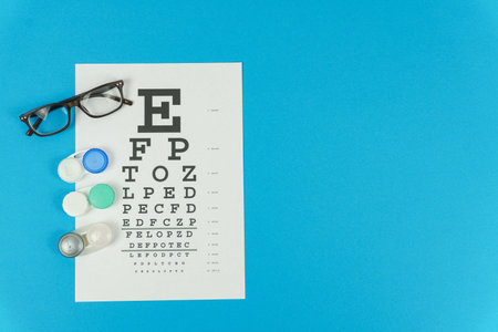 Glasses,lenses and a vision test table on the left on a blue background