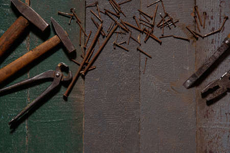 Hammers, pliers, and rusty nails lie on old wooden planks.の写真素材