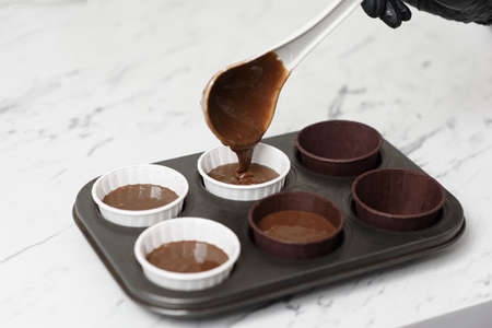 Chocolate cake batter is poured into a mold with beautiful paper cups.の写真素材