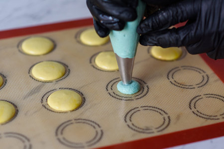 Making macaroons.A cook makes macaroons by squeezing dough out of a cooking syringe onto a baking...
