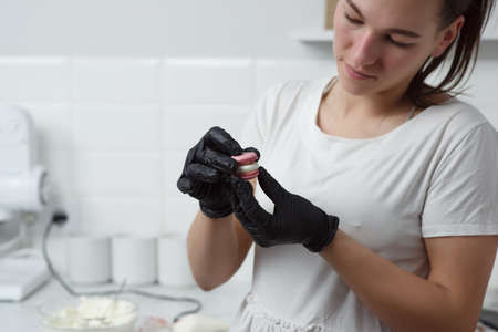 Making macaroons.Pastry chef girl connects two halves of macaroonsの写真素材